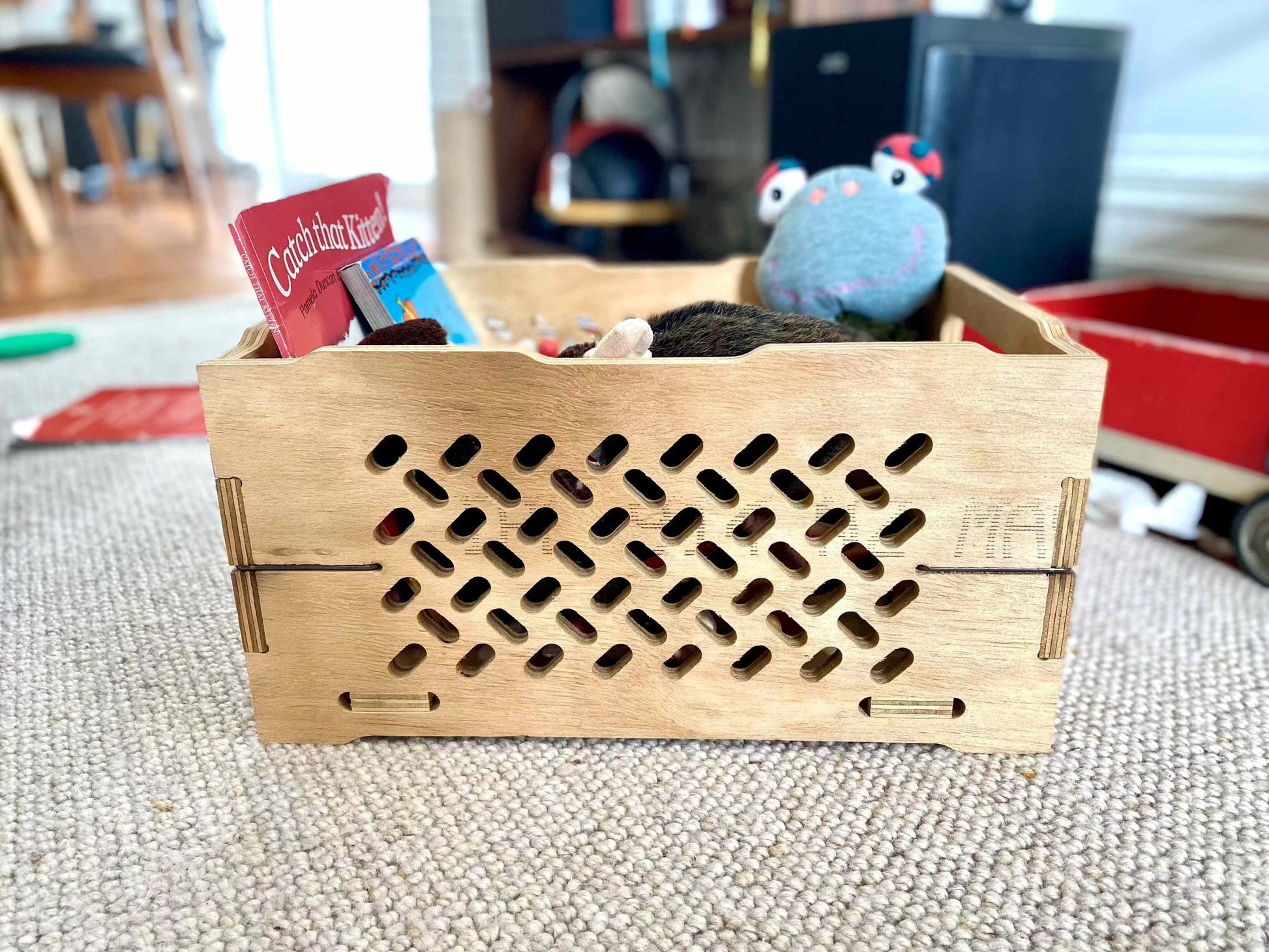 Locally made Wooden toy chest filled with toys on a carpeted floor.