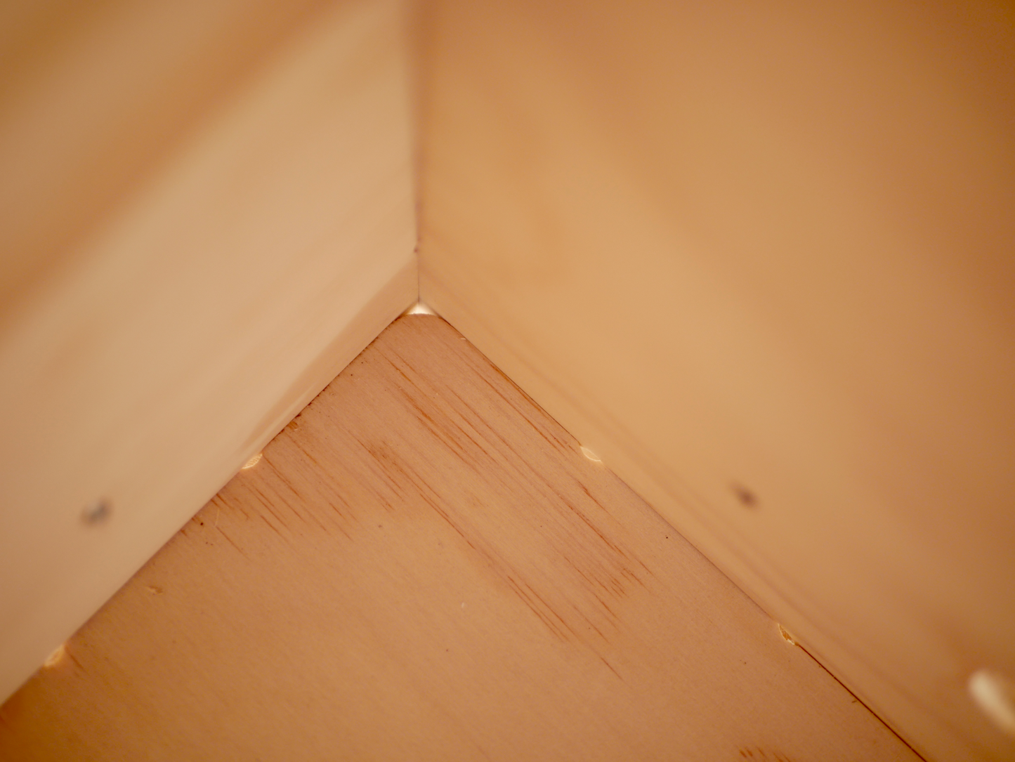 Close-up of the corner of a wooden vinyl storage box with small holes for dust dispersion.