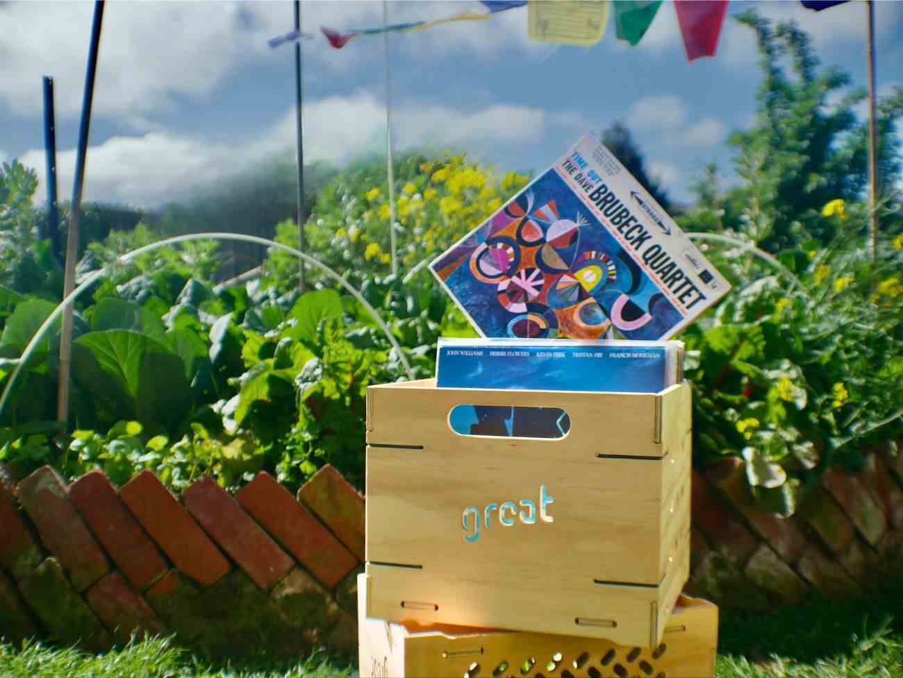 NZ-made vinyl storage box with records, crafted from plywood, beeswax, and steel, in garden setting.